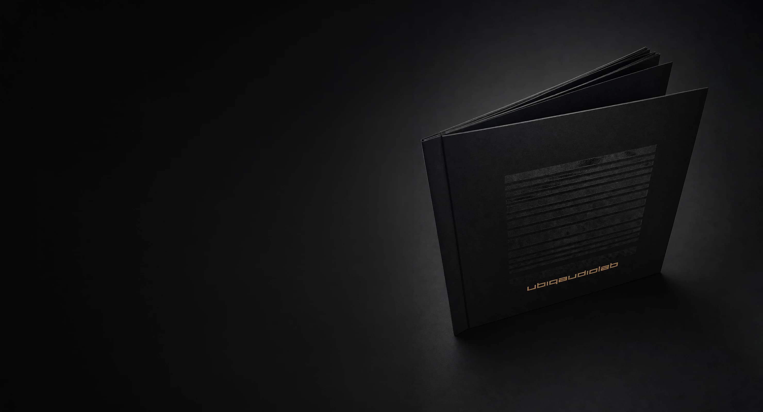 The ubiqaudiolab catalogue, a black hardcover book with the copper wordmark, standing open