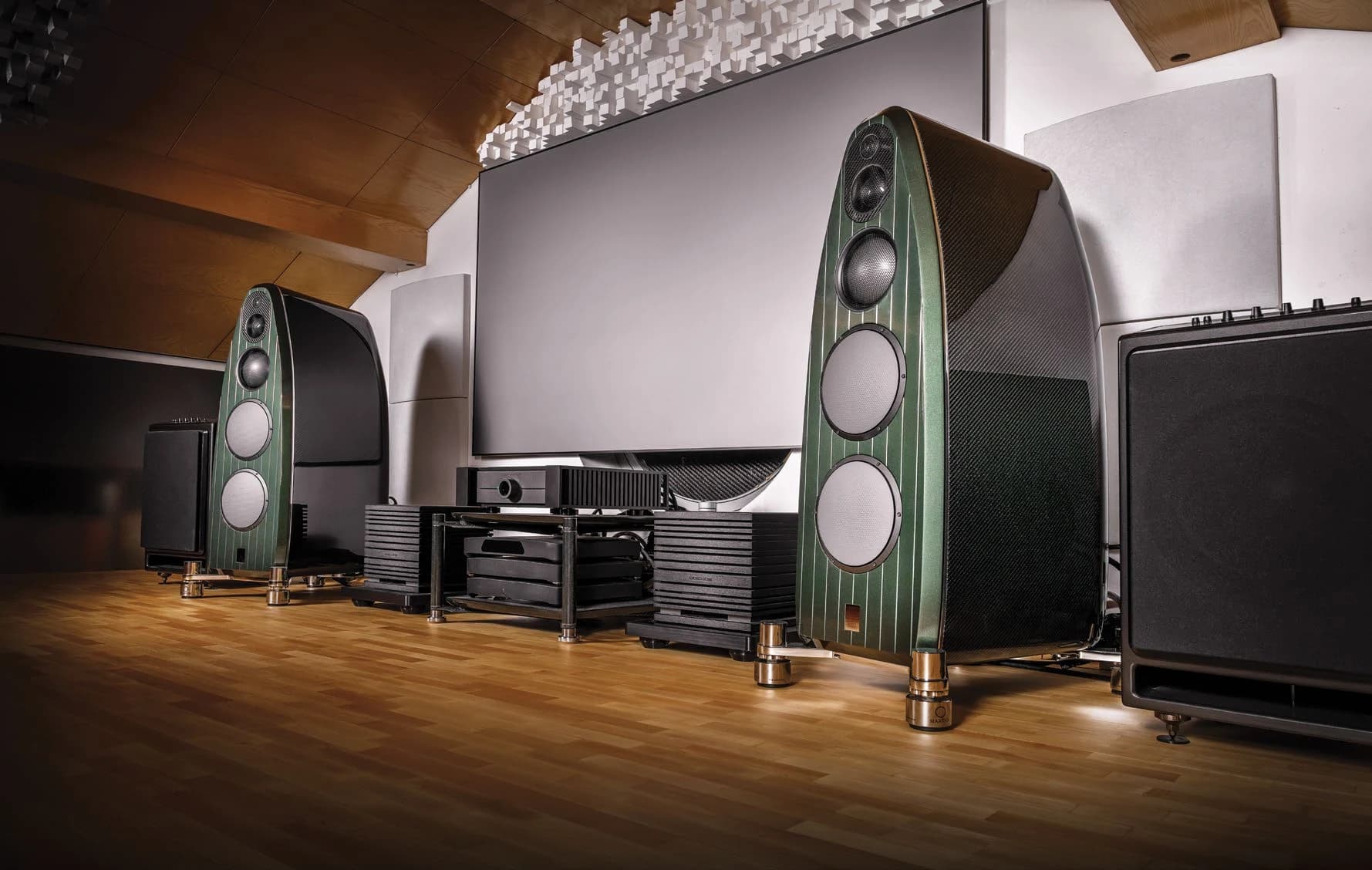 Listening room with green loudspeakers either side of a projection screen and UBICUBE amplifiers between them