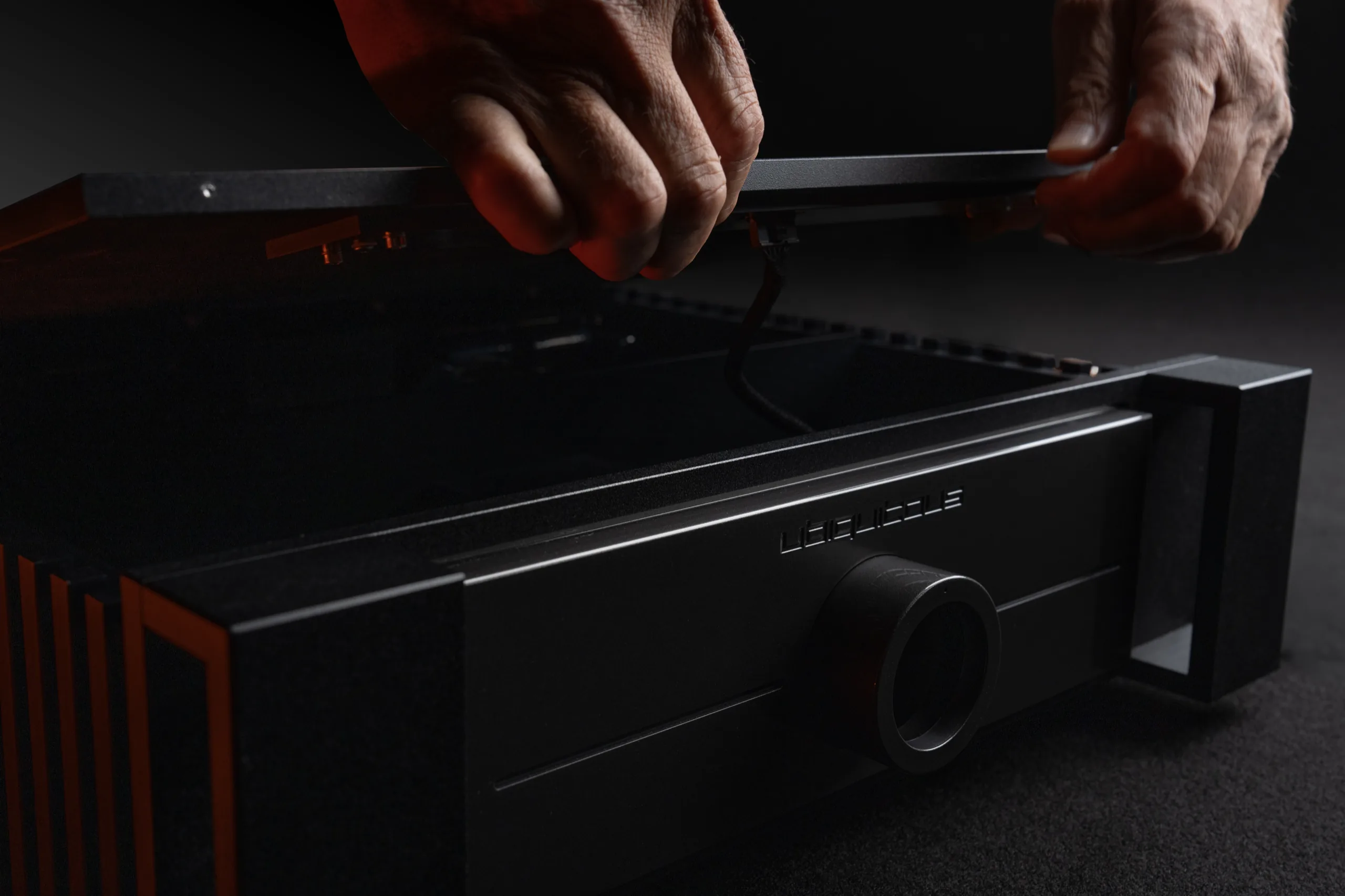 Hands lifting the top plate off a ubiqaudiolab amplifier