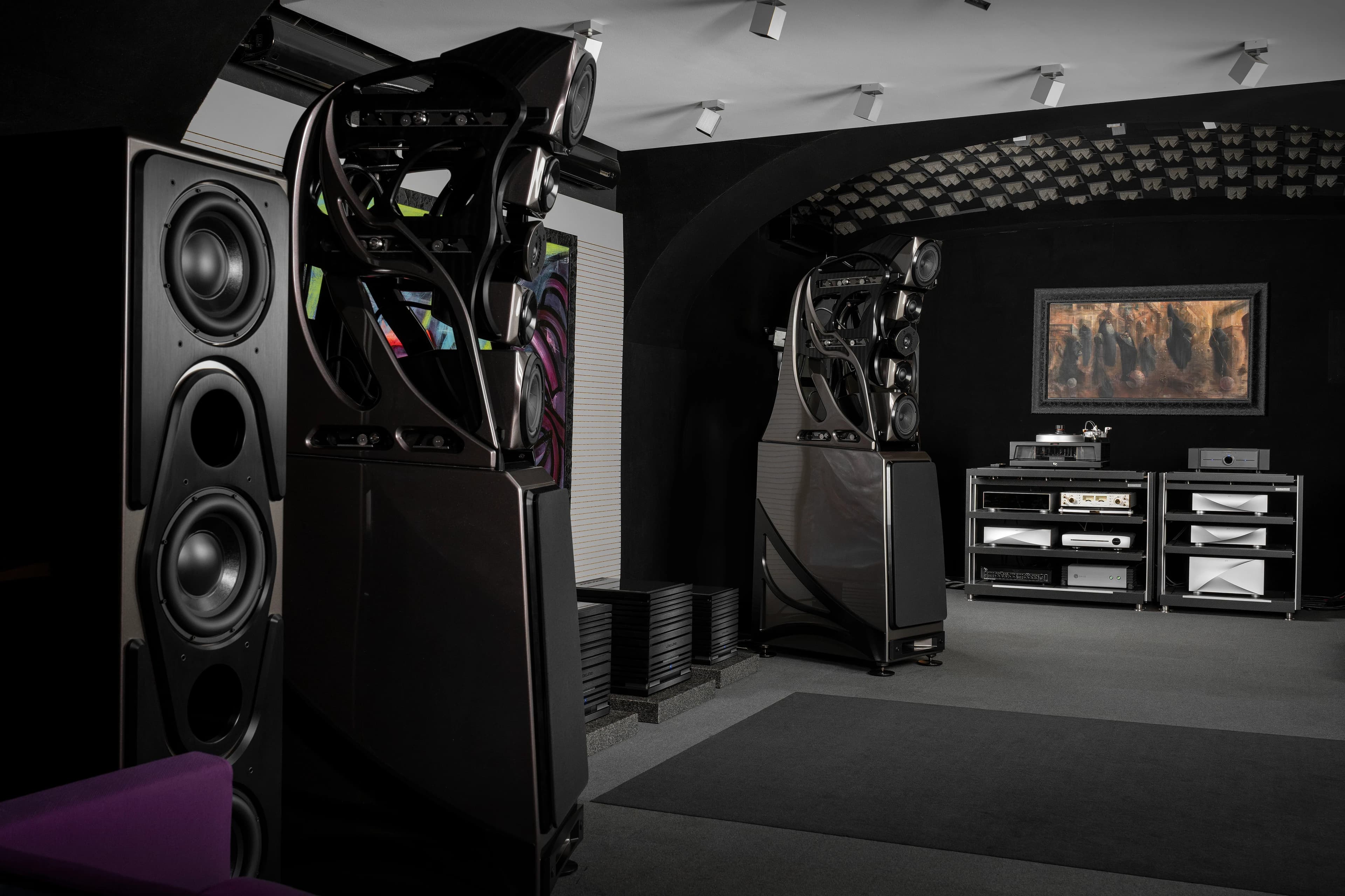 Listening room with large loudspeakers and two equipment racks below a framed painting