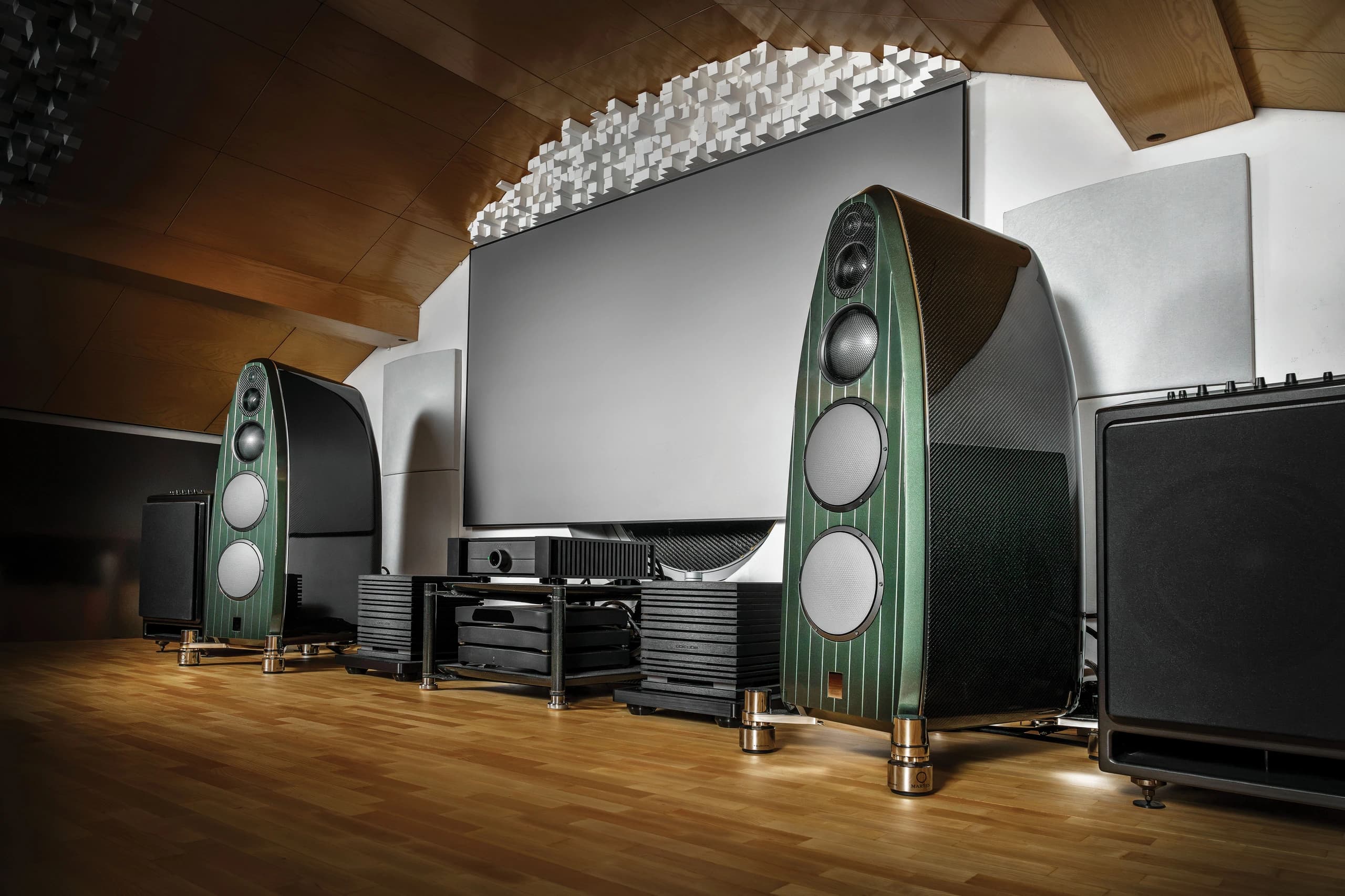 Listening room with green loudspeakers either side of a projection screen and UBICUBE amplifiers between them